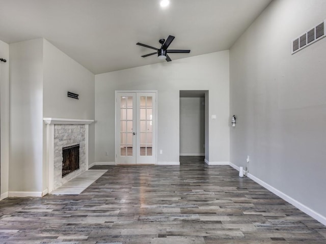 unfurnished living room featuring ceiling fan, wood-type flooring, a fireplace, vaulted ceiling, and french doors