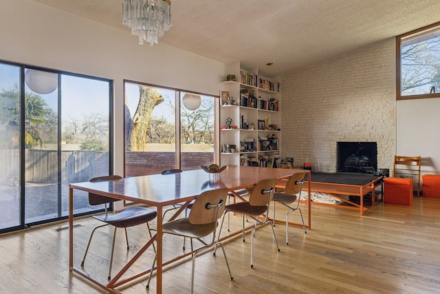 dining area featuring a fireplace, a notable chandelier, light hardwood / wood-style flooring, and a textured ceiling