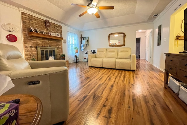 living room featuring a raised ceiling, ceiling fan, hardwood / wood-style floors, and a textured ceiling