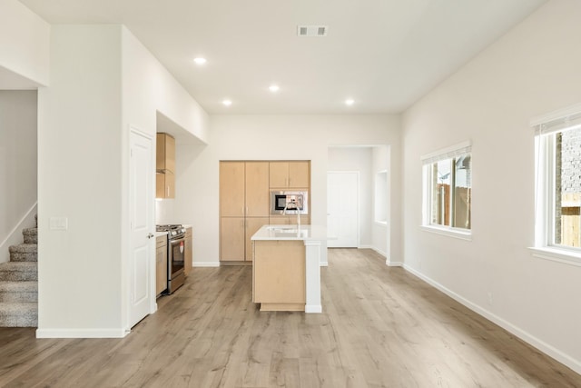 3219 Blossom Trl, Crandall, TX 75114 - kitchen with appliances with stainless steel finishes, light brown cabinets, light wood finished floors, an island with sink, and light countertops