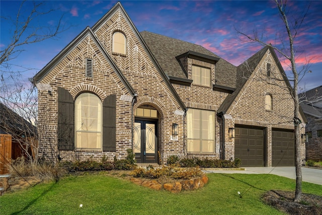 view of front of property featuring a garage, a yard, and french doors