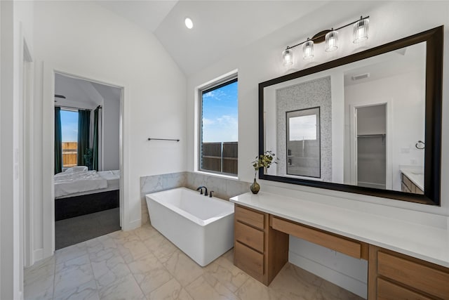 bathroom featuring lofted ceiling, vanity, and a bathing tub