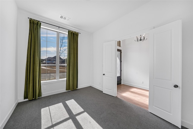 carpeted empty room featuring a notable chandelier