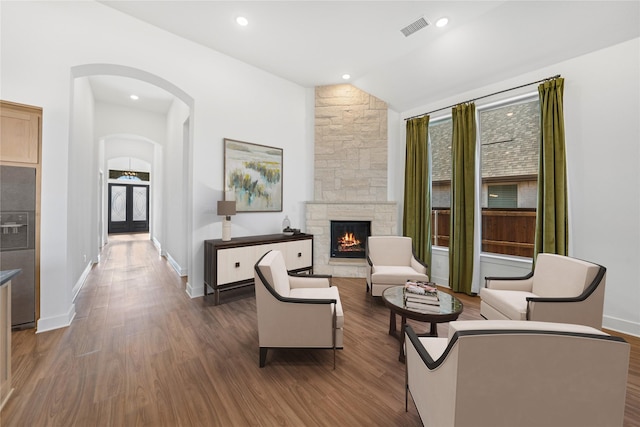 interior space featuring lofted ceiling, a stone fireplace, and dark wood-type flooring