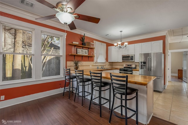 kitchen featuring wood counters, a breakfast bar, white cabinets, and appliances with stainless steel finishes