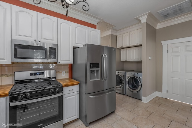 kitchen with stainless steel appliances, washer and dryer, white cabinets, and wood counters