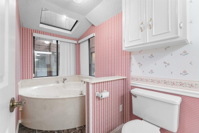 bathroom featuring a washtub, a textured ceiling, and toilet