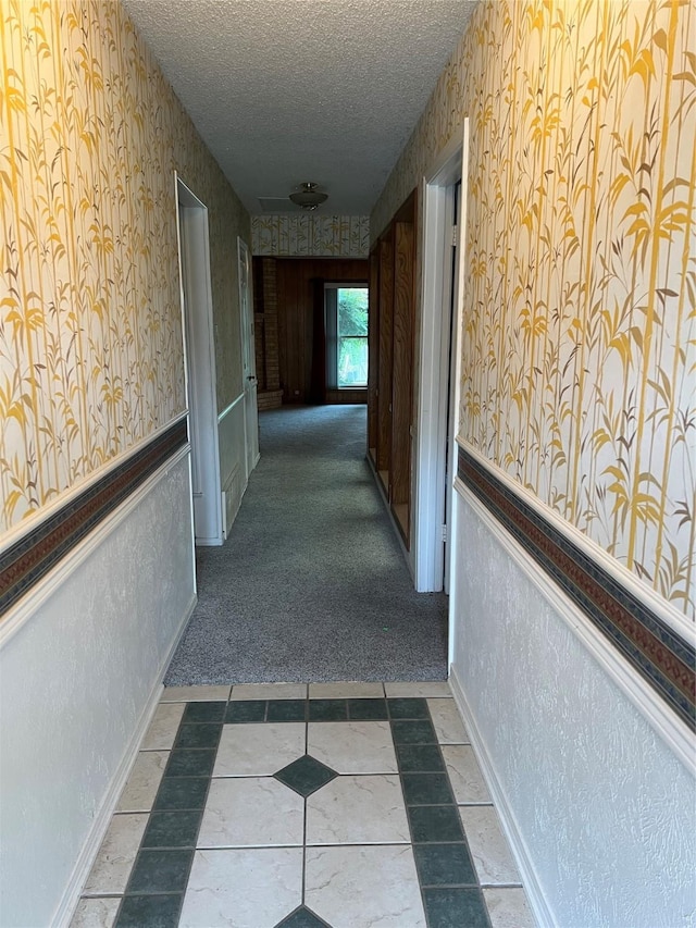 hall with carpet flooring and a textured ceiling