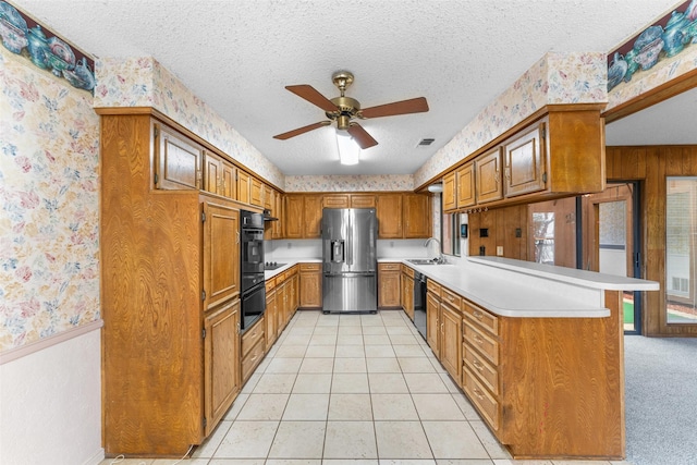 kitchen featuring black appliances, sink, light tile patterned floors, kitchen peninsula, and a textured ceiling