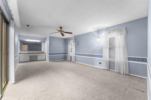 unfurnished living room featuring ceiling fan, carpet flooring, and a textured ceiling