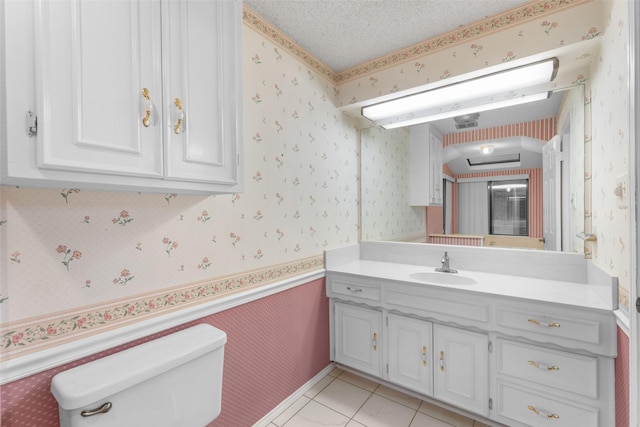 bathroom with tile patterned floors, vanity, toilet, and a textured ceiling