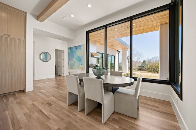 dining area featuring beamed ceiling, baseboards, and light wood-type flooring