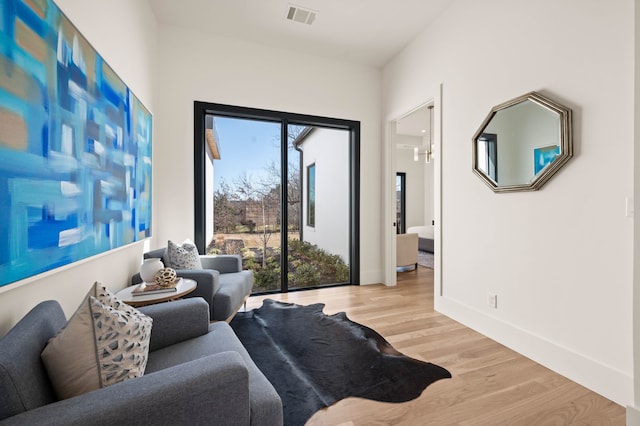 living room featuring baseboards, visible vents, and light wood finished floors