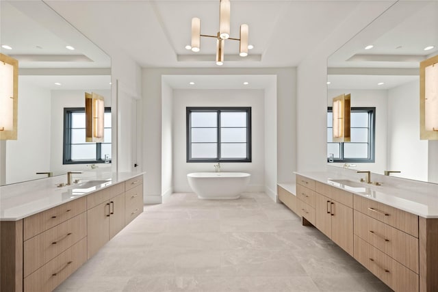 bathroom featuring a raised ceiling, a healthy amount of sunlight, and a sink