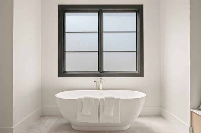 bathroom featuring a soaking tub and baseboards