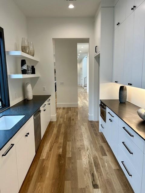 kitchen with dark countertops, wood finished floors, and stainless steel dishwasher