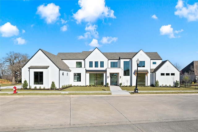 modern farmhouse with a front lawn and stucco siding