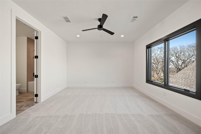 unfurnished room with light carpet, visible vents, baseboards, and a ceiling fan