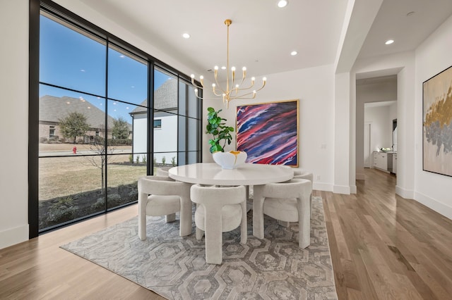 dining space featuring recessed lighting, a notable chandelier, wood finished floors, and baseboards