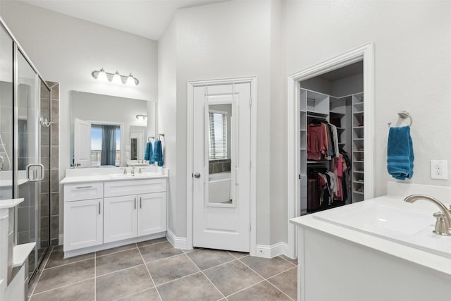 full bathroom featuring plenty of natural light, tile patterned flooring, a walk in closet, and two vanities