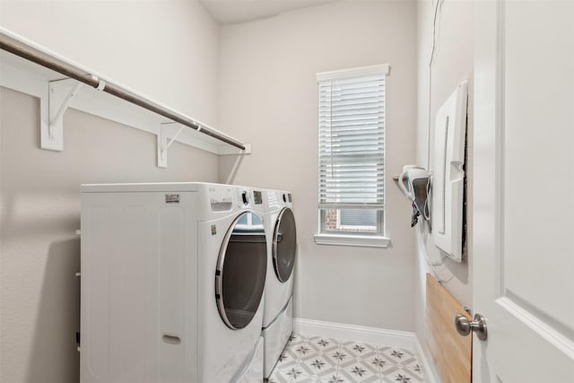 clothes washing area featuring light floors, laundry area, baseboards, and separate washer and dryer