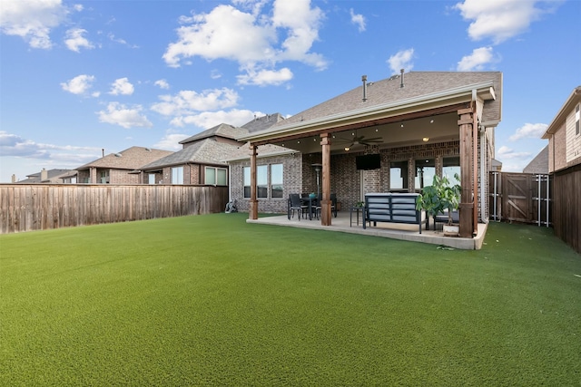 rear view of property featuring a patio, ceiling fan, a fenced backyard, a yard, and brick siding