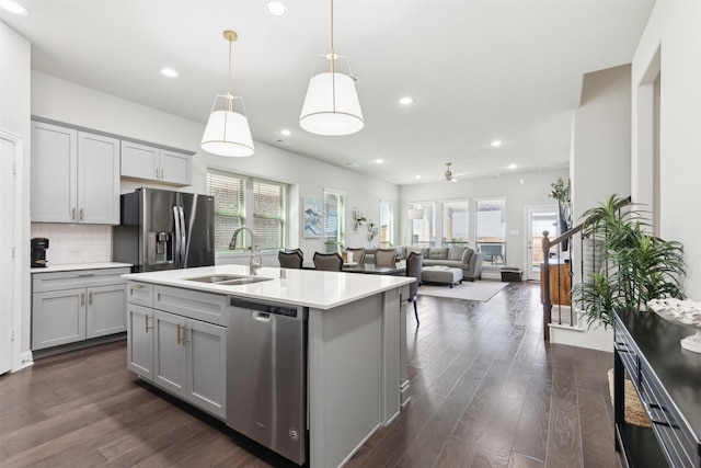 kitchen with pendant lighting, sink, gray cabinets, a kitchen island with sink, and stainless steel appliances