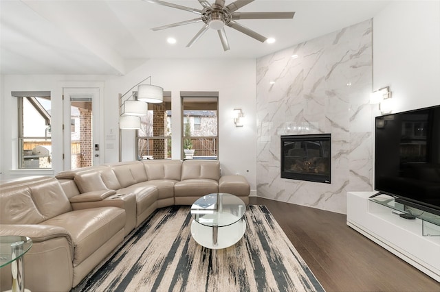 living room with hardwood / wood-style flooring, ceiling fan, a fireplace, and tile walls