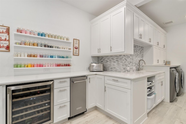 kitchen featuring wine cooler, white cabinetry, washer and clothes dryer, and backsplash