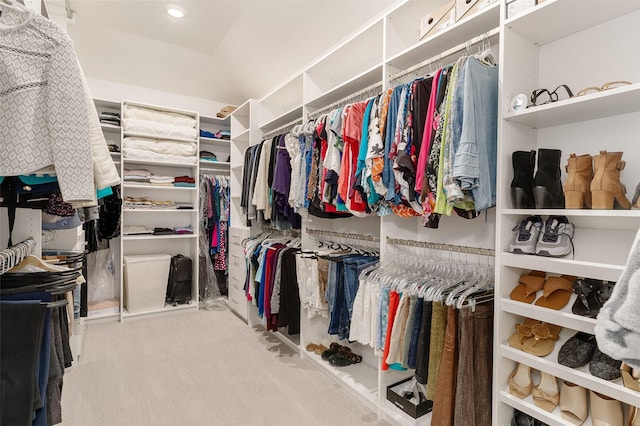 walk in closet with light carpet and vaulted ceiling