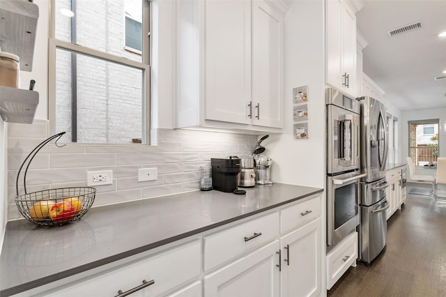 kitchen with white cabinetry, stainless steel appliances, dark wood-type flooring, and decorative backsplash