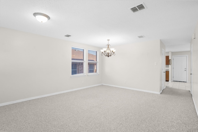 carpeted spare room featuring a chandelier