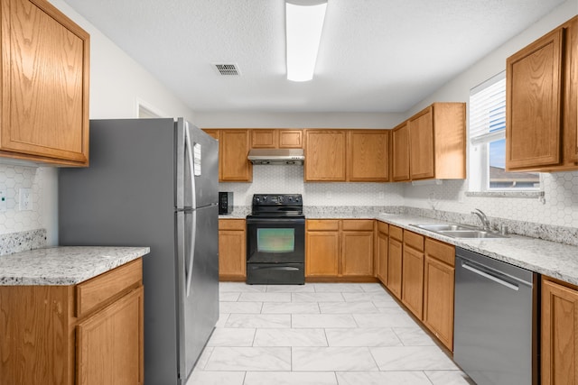 kitchen featuring sink, tasteful backsplash, a textured ceiling, appliances with stainless steel finishes, and light stone countertops