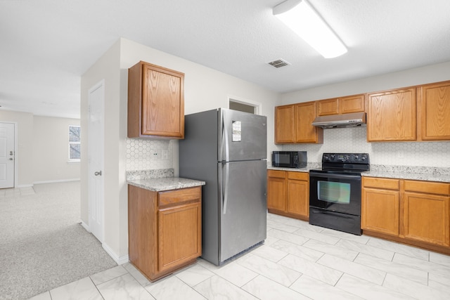 kitchen featuring backsplash, light stone countertops, a textured ceiling, and black appliances