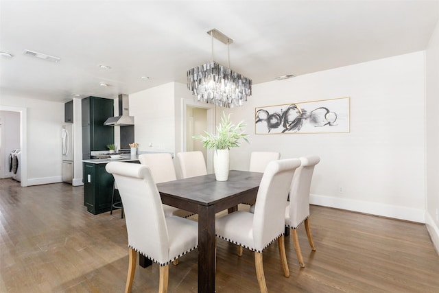 dining space featuring dark wood-type flooring, washer / clothes dryer, and a chandelier