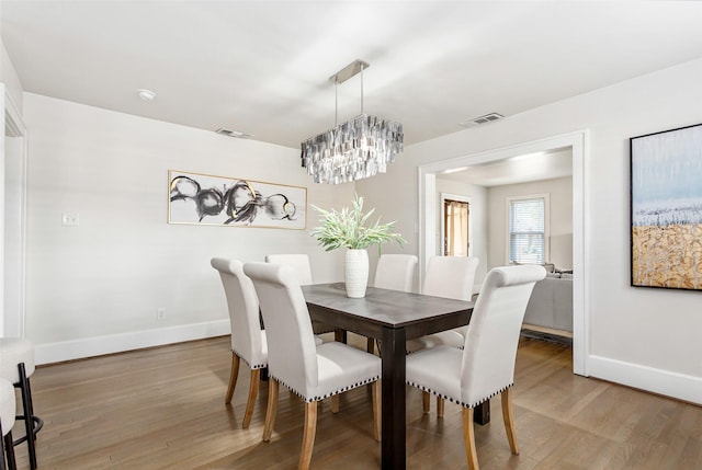 dining room with hardwood / wood-style floors and an inviting chandelier