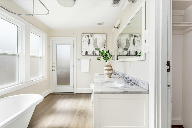 bathroom featuring vanity, a bath, hardwood / wood-style floors, and plenty of natural light