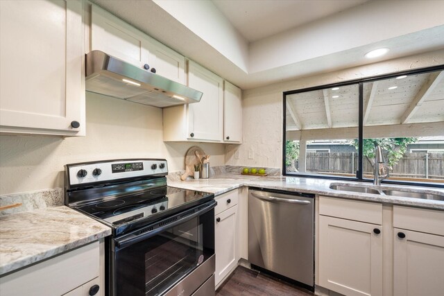 kitchen with sink, white cabinetry, appliances with stainless steel finishes, dark hardwood / wood-style flooring, and light stone countertops