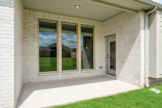 view of exterior entry with a patio area and brick siding