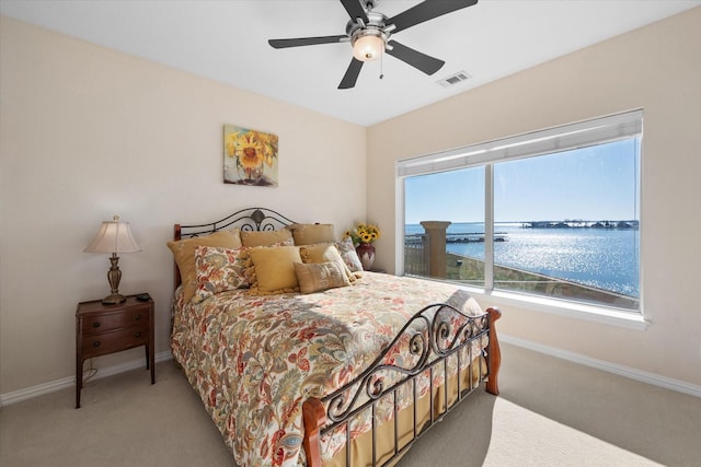 bedroom featuring a water view, carpet floors, and ceiling fan