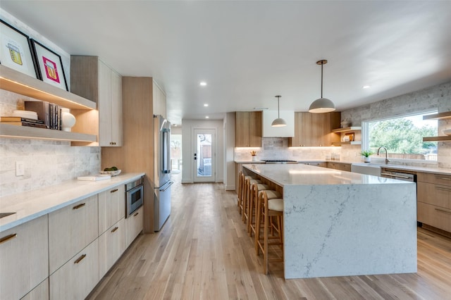 kitchen featuring pendant lighting, light hardwood / wood-style flooring, high end fridge, light stone counters, and a kitchen island