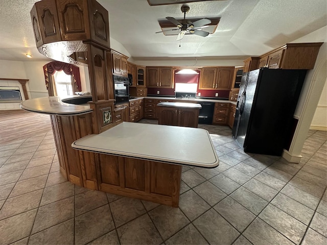 kitchen with light tile patterned floors, ceiling fan, a center island, black appliances, and a textured ceiling