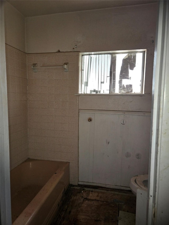 bathroom with toilet, tile walls, and a tub