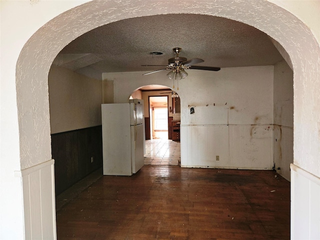 spare room with dark hardwood / wood-style flooring, ceiling fan, and a textured ceiling