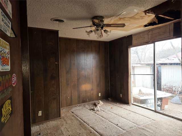 empty room with ceiling fan, carpet floors, a textured ceiling, and wooden walls