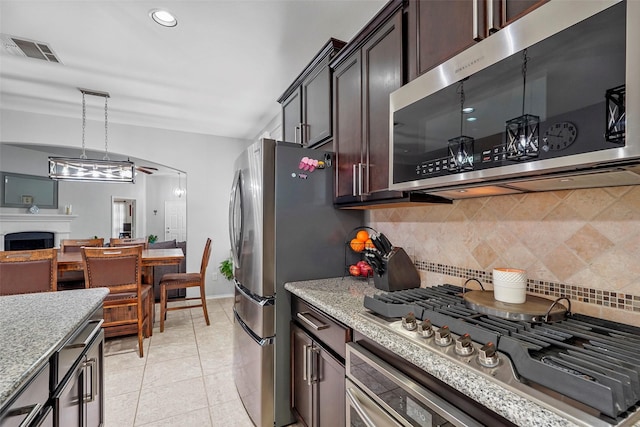 kitchen with light tile patterned flooring, appliances with stainless steel finishes, backsplash, hanging light fixtures, and dark brown cabinets