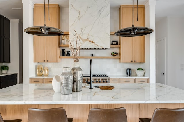 kitchen featuring decorative light fixtures, a breakfast bar area, and light stone countertops