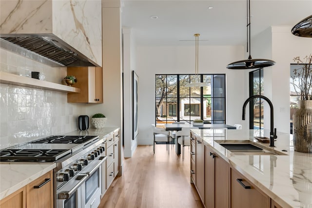 kitchen featuring sink, hanging light fixtures, light stone counters, custom exhaust hood, and range with two ovens