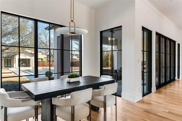 dining room with ornamental molding and light wood-type flooring