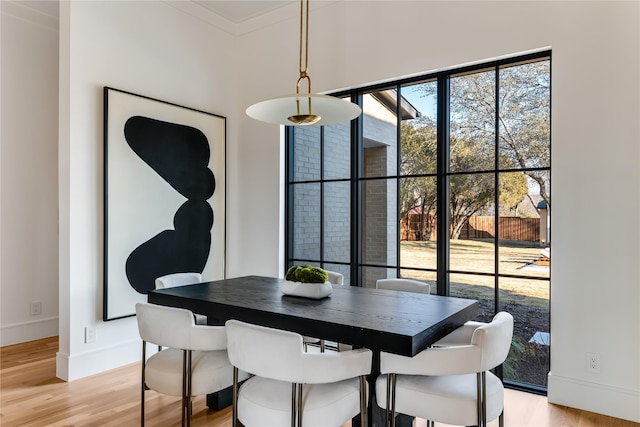 dining area with crown molding and light wood-type flooring